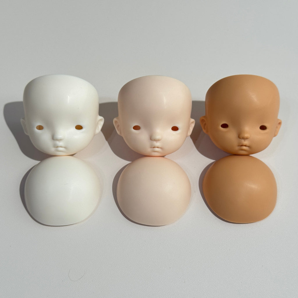 Three dolls with different skin tones on spherical bases against a plain background
